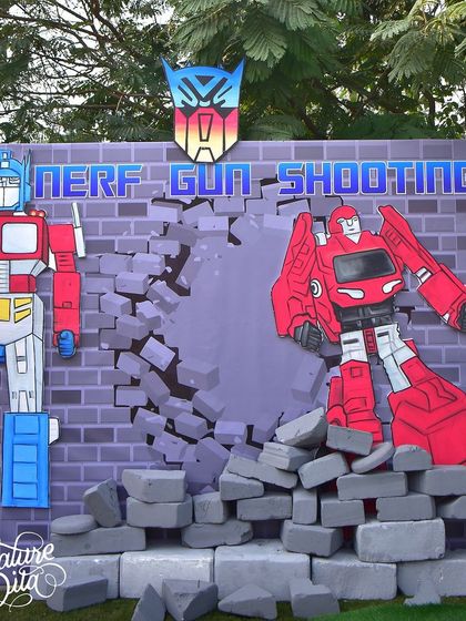 An action-packed Nerf gun shooting range was a central activity at the Transformers party. The custom backdrop features Optimus Prime and another Autobot breaking through a brick wall, creating an exciting target zone.