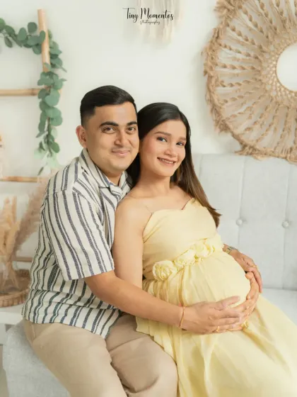 A classic seated pose that feels both comfortable and connected, showcasing the beautiful baby bump as the center of your shared world.