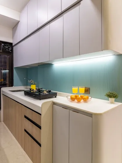 A complete kitchen transformation designed for efficiency and style. We used a refreshing palette of pastel blue fluted tiles, light wood, and grey laminates, along with clever storage, to create a bright, airy, and highly functional culinary space.