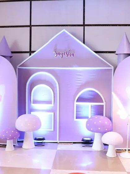 A custom-built purple fairy castle serves as the main photo backdrop. The design includes soft lighting and adorable mushroom props to create a complete fantasy world for the birthday girl.