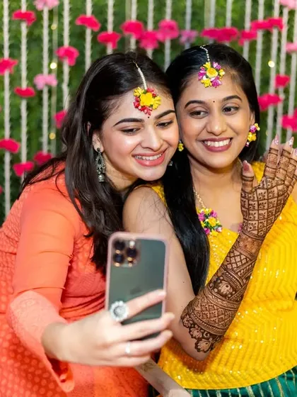 A modern moment at a traditional ceremony. The bride takes a selfie with her friend, capturing the fun of the day.