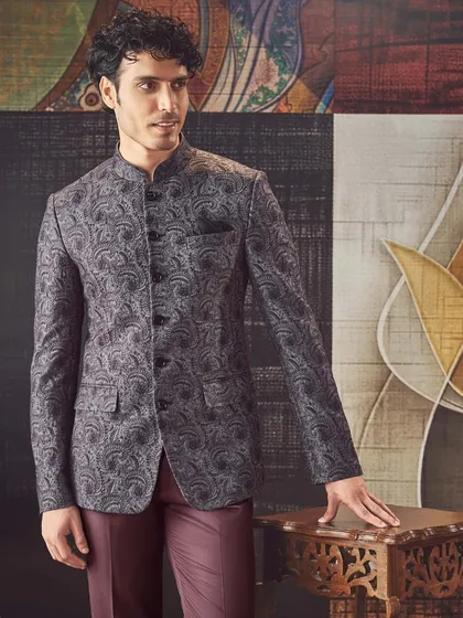 A paisley-patterned Jodhpuri jacket in a distinguished grey. Paired with deep maroon trousers, this ensemble balances heritage motifs with a contemporary color palette.