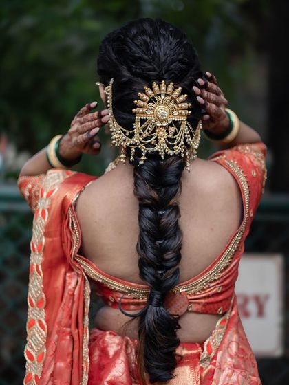 A focus on the traditional hairstyle, showing a braided look with a stunning gold hair accessory called an 'ambada'.