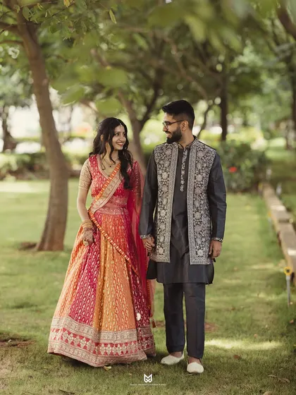 A wider shot of the couple during their outdoor Roka ceremony photoshoot. This shows off their beautiful outfits against the lush greenery.