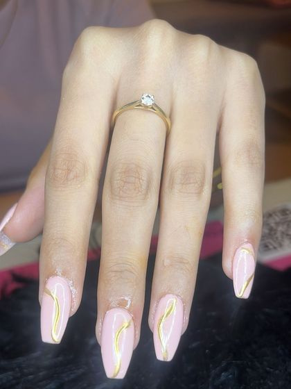 Isolated gold chrome art on pink coffin-shaped extensions for a minimalist yet glam look.