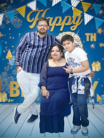 A family portrait against a 'Happy Birthday' backdrop. This photo shows a relaxed moment between parents and their son during his birthday celebration.