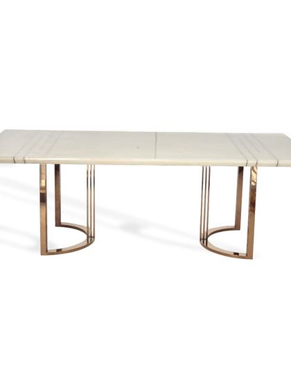 This dining table is designed for cozy family gatherings. It features a light marble top with linear inlay details and a rose gold PVD coated steel base with a distinctive U-shaped frame.