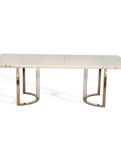 This dining table is designed for cozy family gatherings. It features a light marble top with linear inlay details and a rose gold PVD coated steel base with a distinctive U-shaped frame.