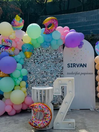 A sweet Candy Land theme with ice cream and donut shaped foil balloons, a pastel balloon arch, and a "2" marquee number.