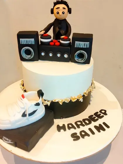 A custom cake for a DJ, featuring a miniature DJ console with speakers, a figurine, and a cool Nike shoe on the side. It perfectly combines a passion for music and sneakers.