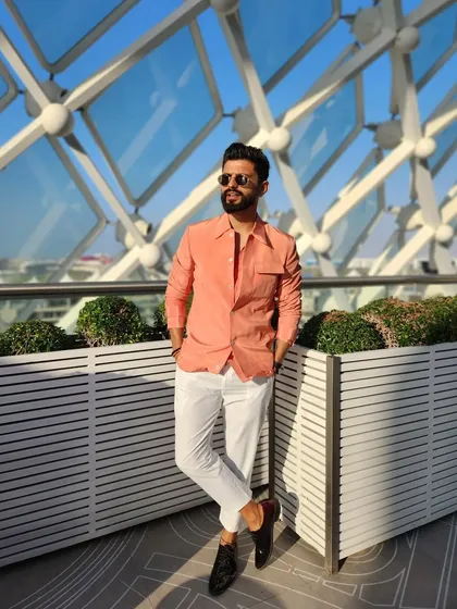 Ready for the baraat in a stylish peach shirt and white pants. A great look for a sunny afternoon celebration.
