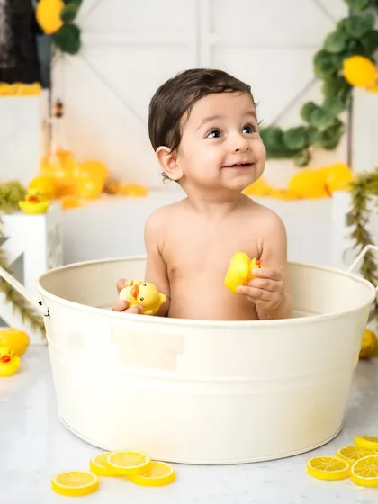 A happy baby in a tub full of rubber duckies. The post-cake-smash splash session is always full of smiles and giggles.