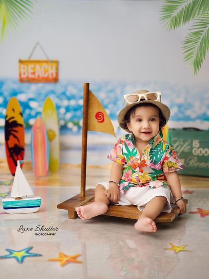 This little beachgoer is all set with his hat and sunglasses, ready for a day of fun. The props and backdrop create a perfect summer vibe.