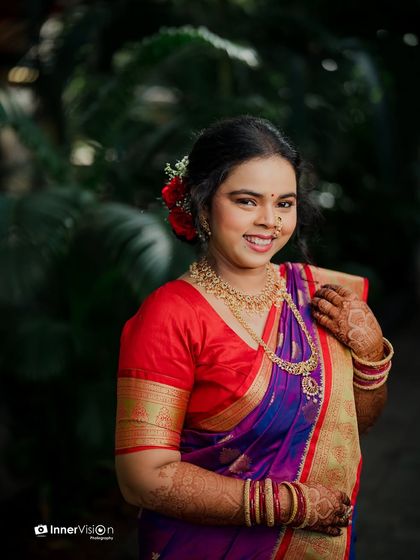 A radiant portrait of the bride against a backdrop of lush green foliage. Her happy expression and colorful saree make for a stunning engagement picture.