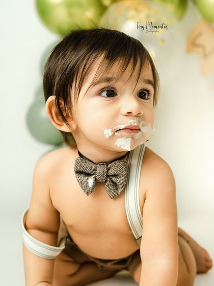 A close-up of the birthday boy, complete with a dapper bowtie and a little bit of frosting. Capturing these sweet details is what makes a cake smash so special.