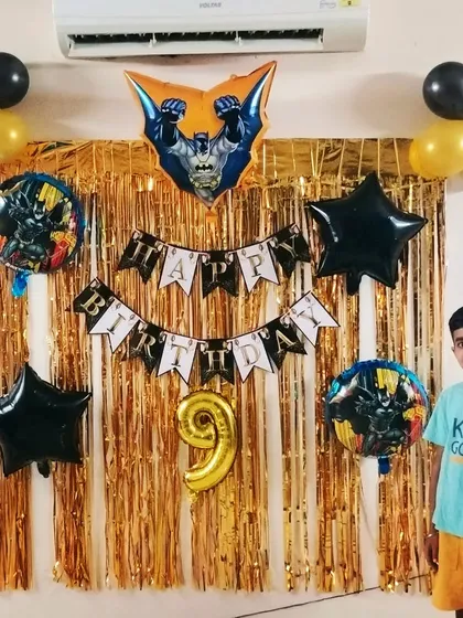 For a young fan of the Dark Knight, we put together this awesome Batman-themed birthday decoration. The setup includes a gold shimmer curtain, a Batman banner, and character-themed foil balloons.