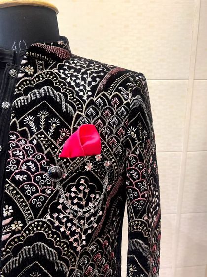 A close-up of the jacket's details, including the button, pocket chain accessory, and the vibrant pink pocket square that adds a pop of color.