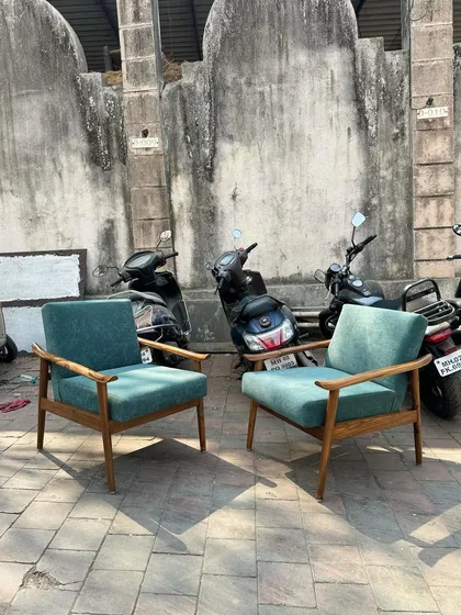 A pair of mid-century lounge chairs with teal upholstery, shown outdoors.