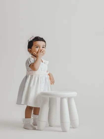 A shy, sweet moment from a toddler session. We use simple props like this white stool to create clean, timeless portraits that highlight your child's expressions.