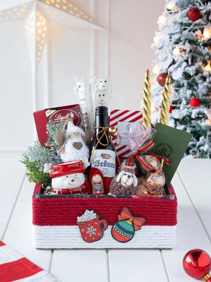 The 'Santa's Sweet Retreat' hamper, beautifully styled in front of a Christmas tree, ready to be placed under the tree for a loved one.
