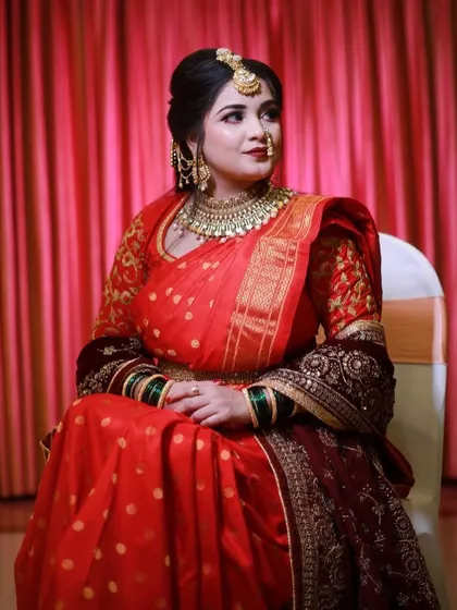 A seated portrait of the bride, her red saree beautifully spread around her, creating a regal and elegant image.