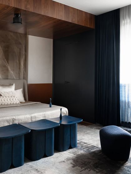 The master bedroom in Scarlet Horizon is a sanctuary of quiet luxury. We wrapped the room in deep night-blue tones, complemented by a wood-paneled ceiling and a statement marble accent wall, to create a moody yet calming retreat reminiscent of a starlit sky.
