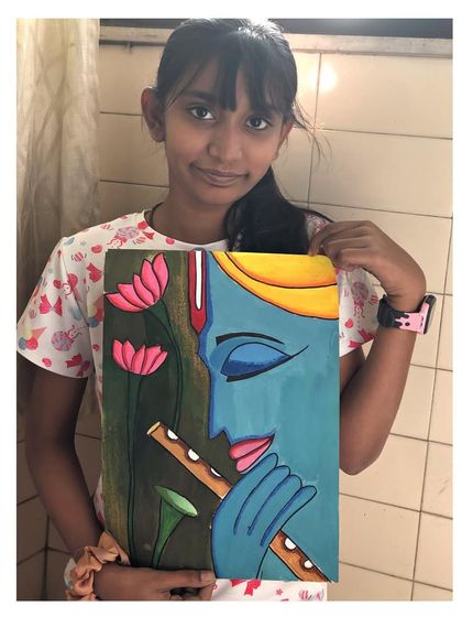 A student holds her beautiful painting of Lord Krishna playing the flute, set against a backdrop of lotus flowers. This piece has a wonderful sense of peace and devotion.