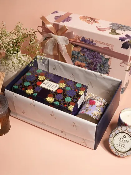 A beautiful gift set featuring a soft, floral color palette. Inside, you'll find a curated selection of our scented candles and a reed diffuser, demonstrating the variety we can include in our bespoke hampers.