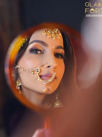 A creative shot capturing the Heeramandi-inspired bridal look in a mirror. The focus is on the expressive eyes, framed by a large nath and maang tikka.