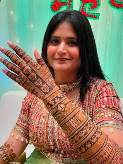 A client showing her mehndi with the initial 'Y' prominently displayed on her hand.