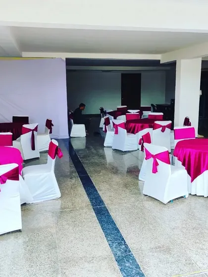 A view of the guest seating area for a housewarming party in Ansal Esencia. We used round tables with bright pink tablecloths and chairs with white covers and matching pink sashes.