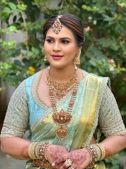 A bride in a pastel blue Kanchipuram saree. Her custom blouse is heavily embroidered with thread and beadwork, matching the grandeur of her traditional temple jewelry.