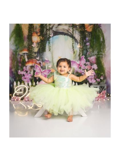 A little fairy in an enchanted forest. The whimsical backdrop and her beautiful dress create a truly magical first birthday portrait.