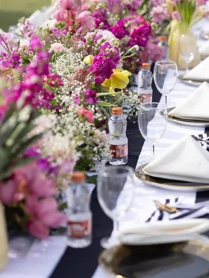 The tablescape for the polo luncheon featured a black-and-white striped runner, complemented by a vibrant mix of pink, purple, and yellow flowers.
