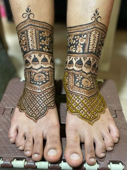 This is part of a step-by-step series showing a bridal foot design in progress. Here you can see the henna paste is still fresh on one foot, while the other is complete.
