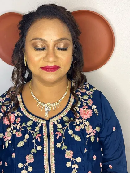 A close-up of the makeup for this client in a blue embroidered outfit. The look features a warm, shimmery eye and a bold red lip.