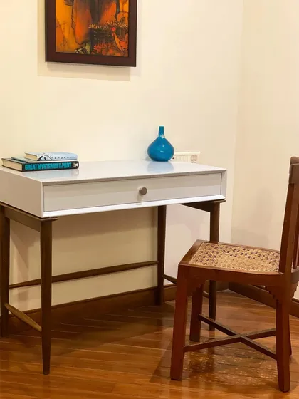 A simple and elegant study corner. This custom-designed desk features a clean white top and a dark wood frame, paired with a classic cane chair for a timeless look.