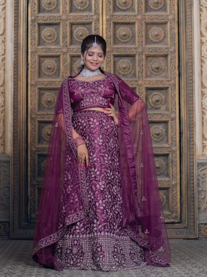 A full-length view of a beautiful purple lehenga with intricate embroidery, paired with a modern diamond necklace.