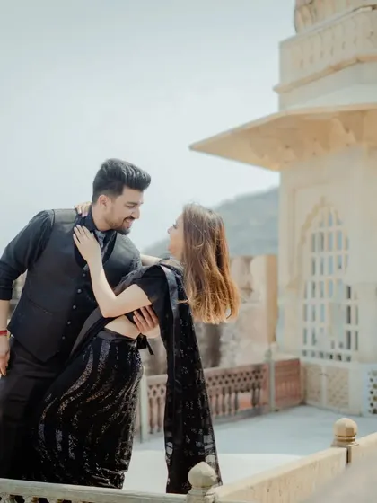 An intimate dance on a palace balcony. The all-black outfits create a chic and modern look that contrasts beautifully with the ancient stone architecture.