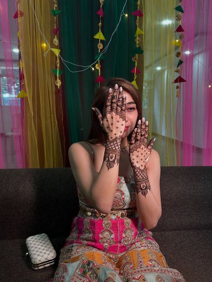 A playful peek through hands decorated with a modern jaali net pattern, perfect for a fun sangeet night.