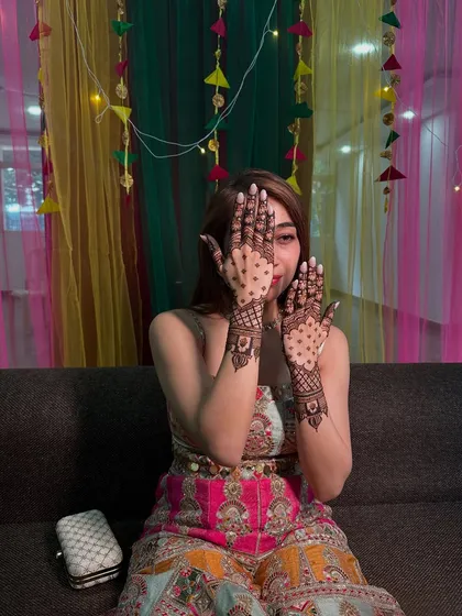 A playful peek through hands decorated with a modern jaali net pattern, perfect for a fun sangeet night.