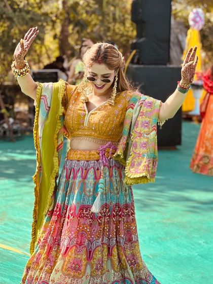 This multicoloured lehenga is made for celebration. The vibrant skirt, paired with a mustard yellow blouse and a lime green dupatta, is full of energy and perfect for a daytime mehendi or a lively sangeet night.