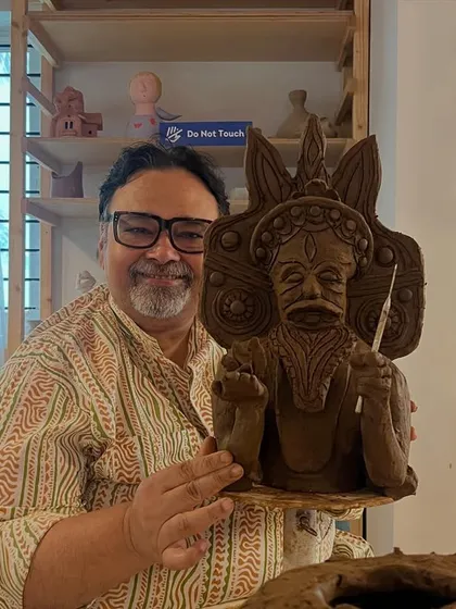 A participant proudly holds his finished sculpture of a traditional character, intricately detailed and full of expression.