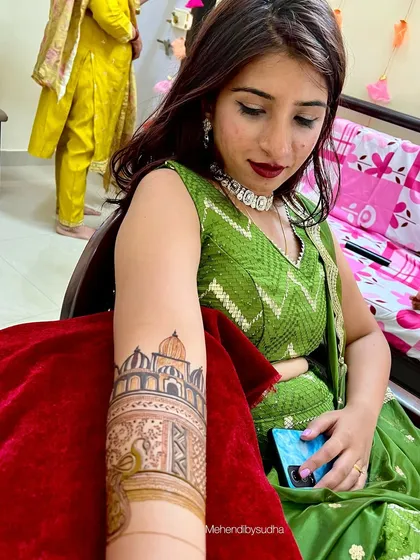 The bride Divya admiring her custom Taj Mahal mehendi, a beautiful and personal piece of art for her special day.