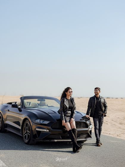 A classic wide shot of the couple and their car on a desert road, capturing the scale and romance of a destination shoot.