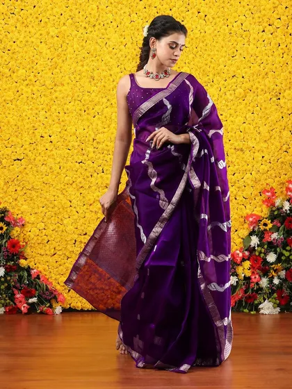 The flowing pallu of the purple and silver saree creates a beautiful and dynamic effect.
