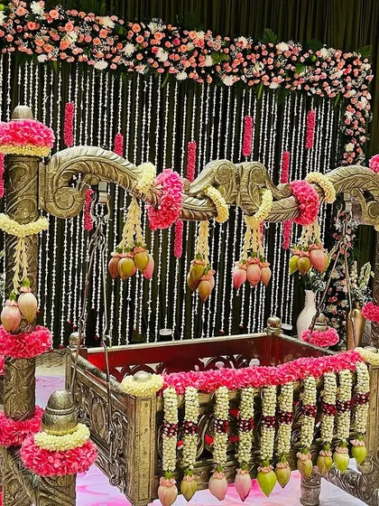 An ornate cradle (thottilu) decorated for a naming ceremony. I used garlands of jasmine and pink flowers, with hanging lotus buds to create a beautiful and auspicious centerpiece for the event.