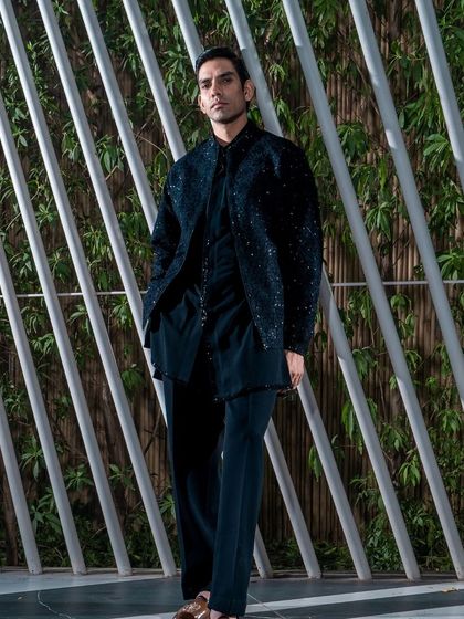 This black Indo-Western ensemble features a jacket with a subtle shimmer, creating a look that is both dapper and understated. It is a versatile choice for any modern celebration.