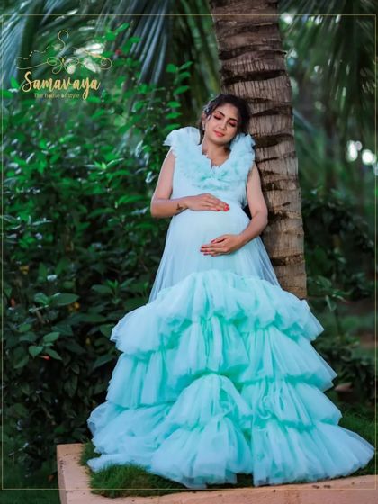 A serene moment as the mother-to-be rests against a tree, her pastel blue frill gown cascading down. This is the picture of tranquility.
