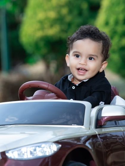 This little driver is cruising in his luxury toy car, enjoying the fresh air.